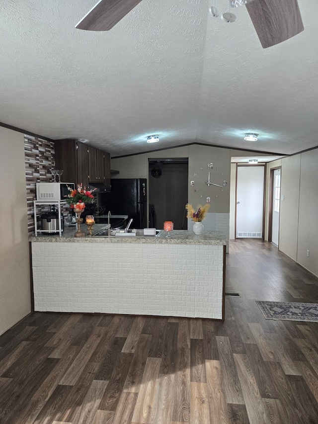 kitchen featuring dark wood-type flooring, dark brown cabinets, kitchen peninsula, and a textured ceiling