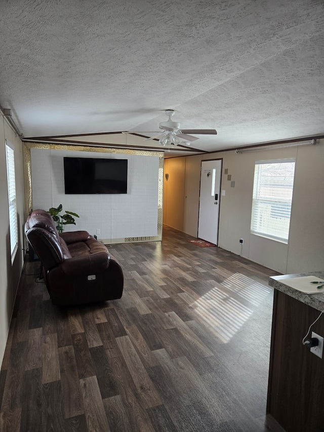 living room featuring ceiling fan, a textured ceiling, and dark hardwood / wood-style flooring