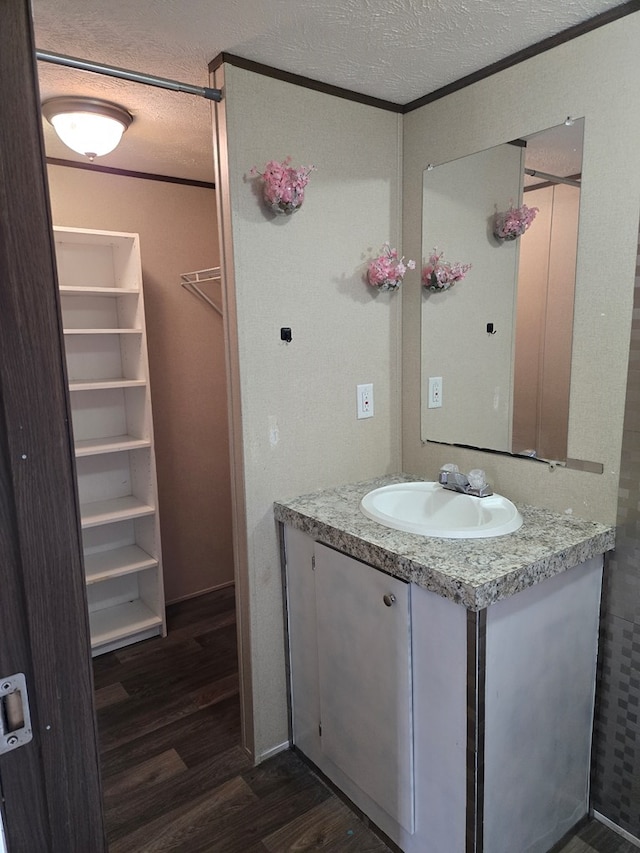 bathroom with vanity, crown molding, hardwood / wood-style floors, and a textured ceiling