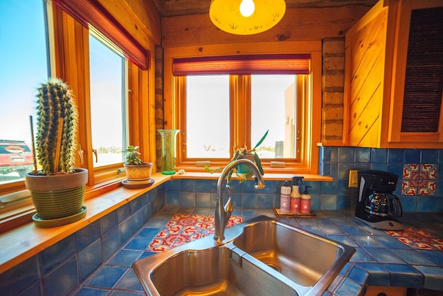 interior details featuring tile countertops, wood walls, sink, and tasteful backsplash