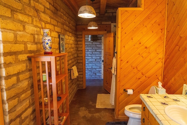 bathroom with sink, brick wall, and toilet