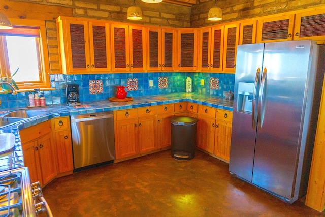 kitchen with tile counters, hanging light fixtures, and appliances with stainless steel finishes