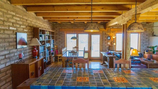 dining space featuring beam ceiling and brick wall