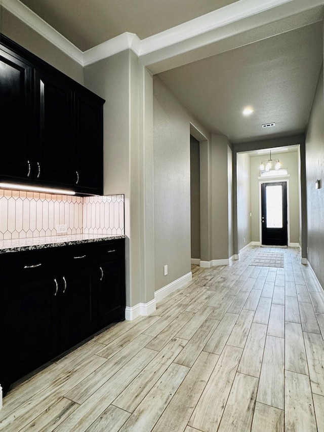 kitchen with light wood-style flooring, dark cabinetry, and baseboards