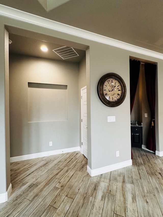 unfurnished room featuring light wood-type flooring, visible vents, and baseboards