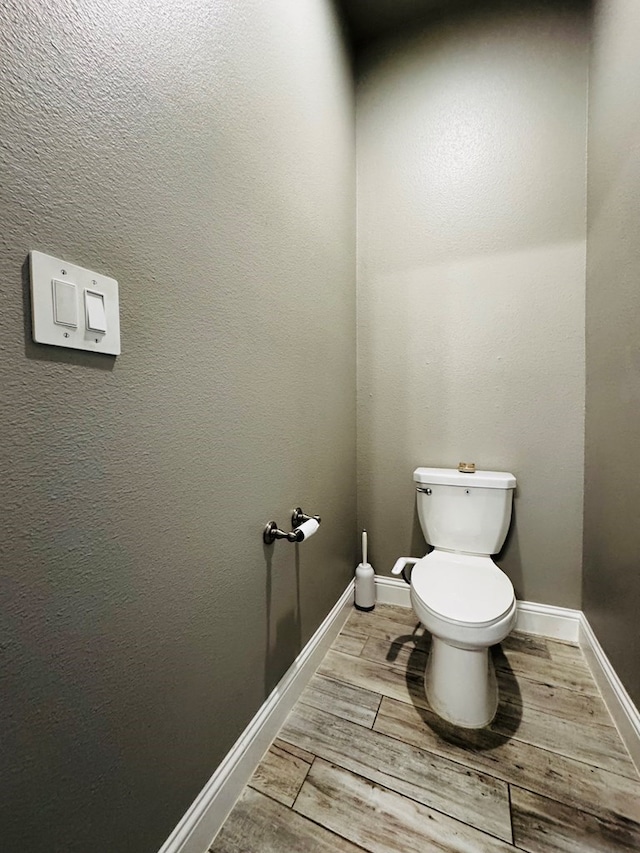 bathroom featuring toilet, baseboards, and wood finished floors