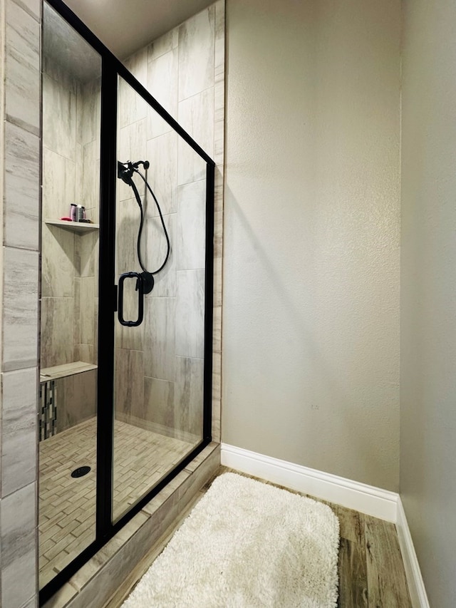 bathroom featuring baseboards, wood finished floors, and a shower stall