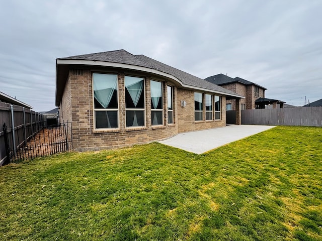 rear view of property featuring a yard, a fenced backyard, brick siding, and a patio