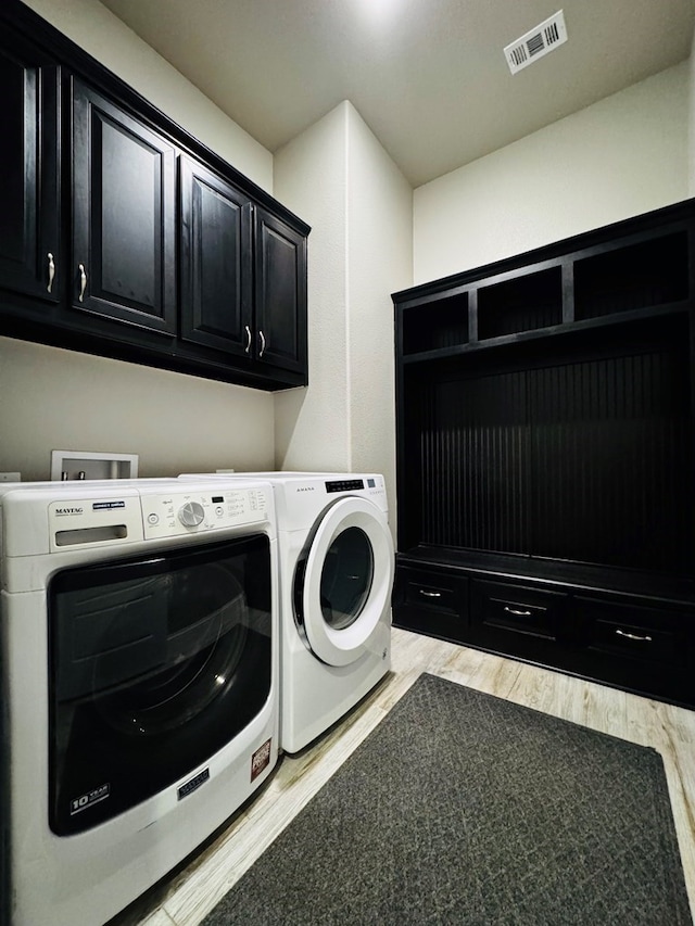 laundry area with light wood-style flooring, cabinet space, visible vents, and washer and clothes dryer