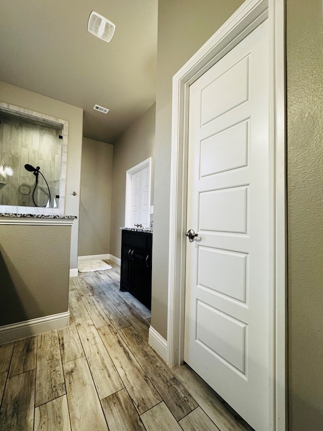 bathroom featuring visible vents, wood finished floors, baseboards, and a walk in shower