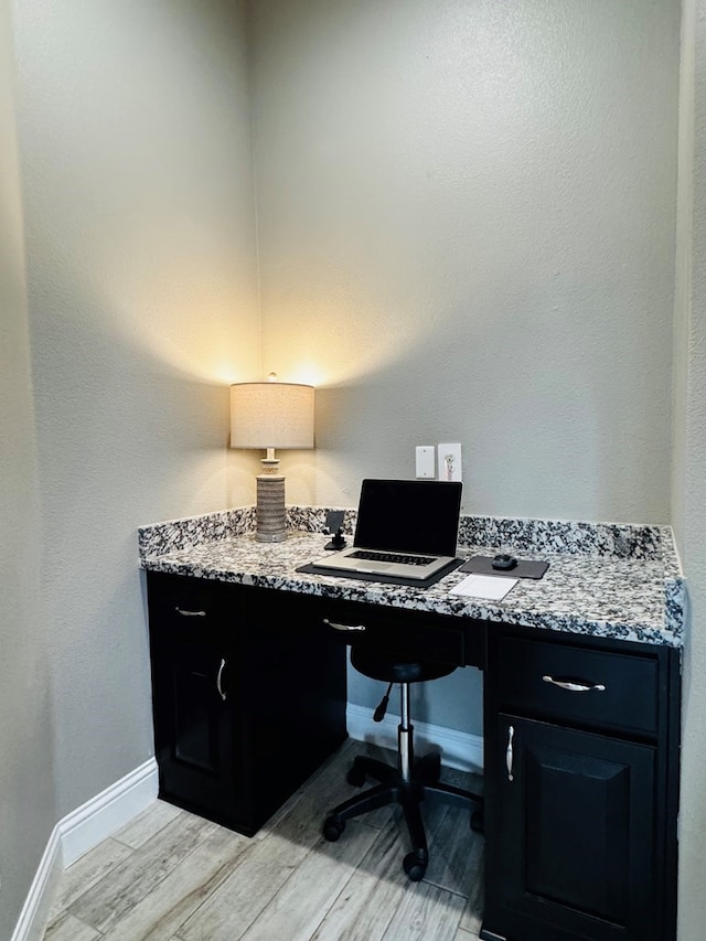 office area with built in desk, light wood-style flooring, and baseboards