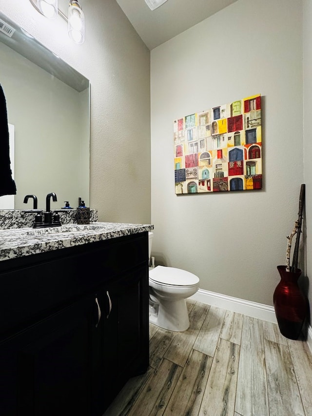 bathroom with visible vents, toilet, wood finished floors, baseboards, and vanity