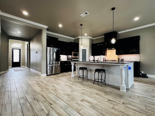 kitchen with visible vents, decorative backsplash, light wood-style flooring, dark cabinetry, and stainless steel appliances