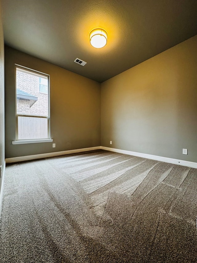 carpeted spare room featuring baseboards and visible vents