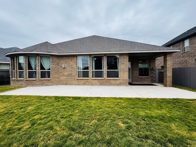 rear view of house featuring a patio, a lawn, brick siding, and fence