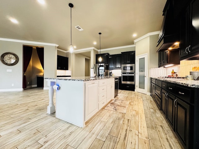 kitchen with visible vents, dark cabinets, stainless steel appliances, decorative backsplash, and light wood-type flooring