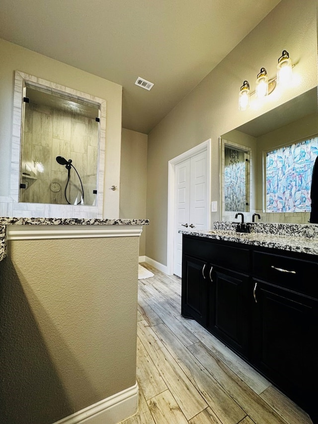 bathroom featuring visible vents, a walk in shower, wood finished floors, baseboards, and vanity