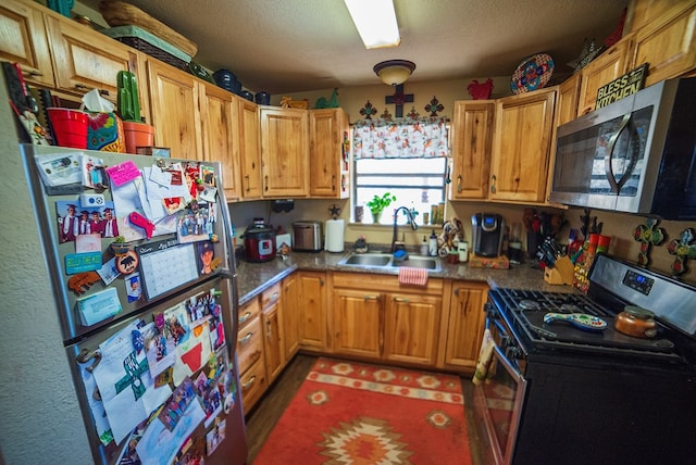 kitchen with appliances with stainless steel finishes, a textured ceiling, and sink