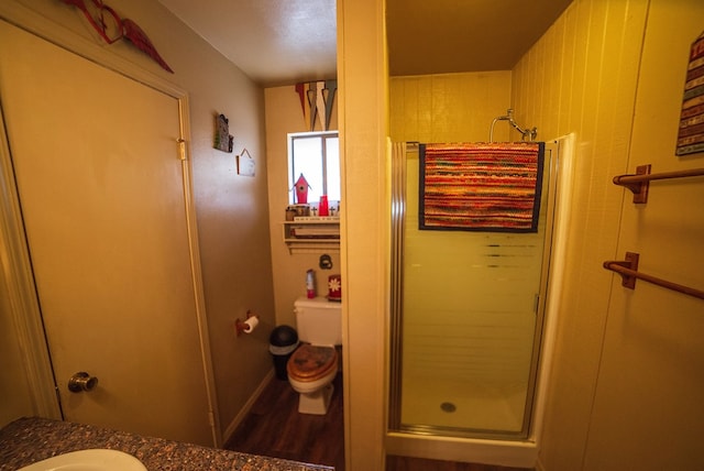 bathroom with hardwood / wood-style floors, toilet, a shower with door, and sink