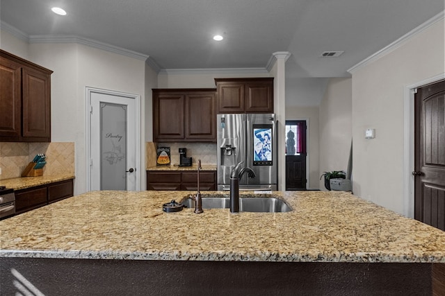 kitchen featuring backsplash, a kitchen island with sink, crown molding, and stainless steel refrigerator with ice dispenser