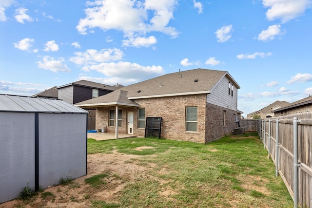 rear view of house with a patio, central AC, and a lawn