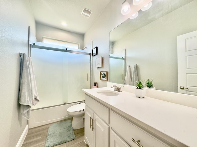 full bathroom featuring combined bath / shower with glass door, vanity, hardwood / wood-style flooring, and toilet