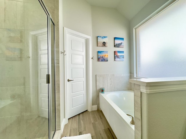 bathroom with wood-type flooring, shower with separate bathtub, and lofted ceiling