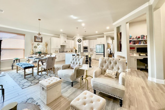 living room featuring a notable chandelier, built in desk, ornamental molding, and light hardwood / wood-style flooring