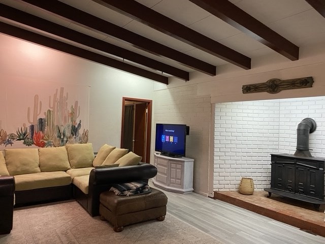 living room featuring hardwood / wood-style flooring, beamed ceiling, and a wood stove