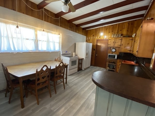 kitchen with sink, white appliances, wooden walls, beamed ceiling, and light wood-type flooring