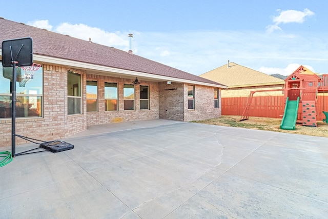 rear view of house featuring a playground and a patio