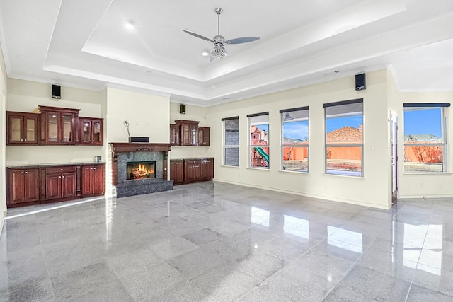 living room featuring ceiling fan, ornamental molding, a raised ceiling, and a premium fireplace