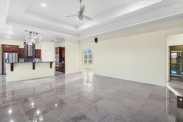 unfurnished living room featuring ceiling fan, crown molding, and a tray ceiling