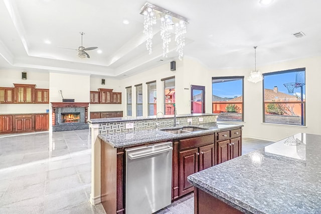 kitchen with pendant lighting, stainless steel dishwasher, sink, a kitchen island with sink, and ceiling fan with notable chandelier