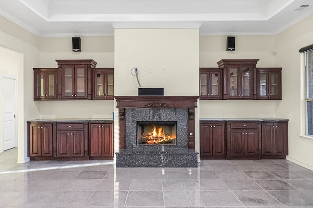 interior space with a high end fireplace, ornamental molding, and a raised ceiling