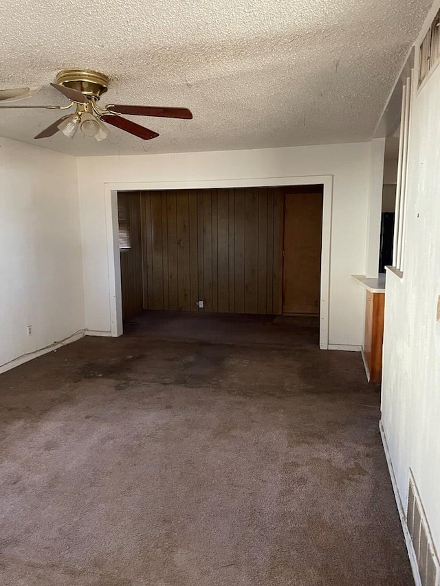 carpeted empty room with ceiling fan and a textured ceiling