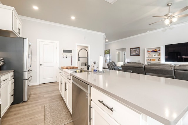 kitchen featuring a sink, ceiling fan, stainless steel appliances, light wood-style floors, and white cabinetry