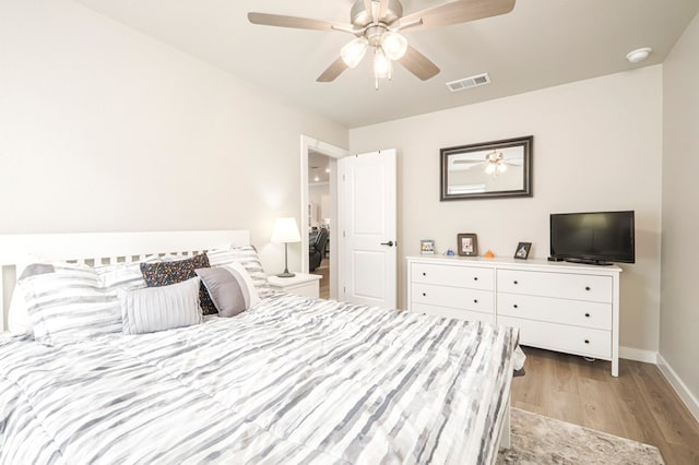 bedroom featuring a ceiling fan, wood finished floors, visible vents, and baseboards