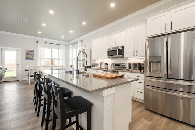 kitchen featuring appliances with stainless steel finishes, a breakfast bar, crown molding, and a kitchen island with sink