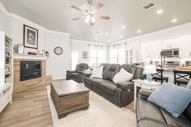 living room featuring visible vents, crown molding, and light wood finished floors