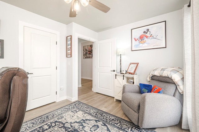 sitting room with ceiling fan, baseboards, and light wood-style flooring