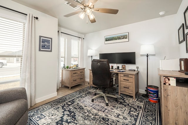 home office with visible vents, baseboards, ceiling fan, and light wood finished floors