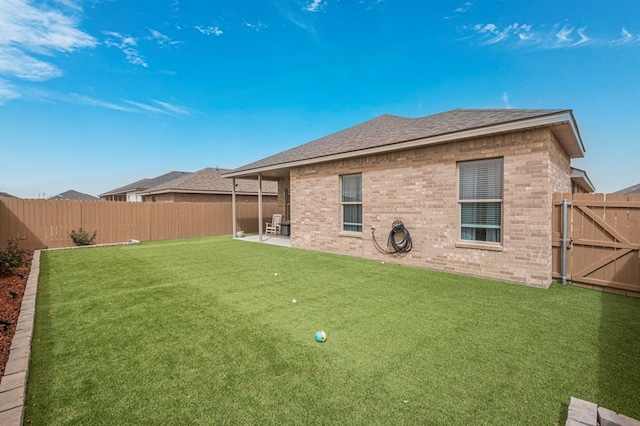 view of yard with a patio area, a fenced backyard, and a gate