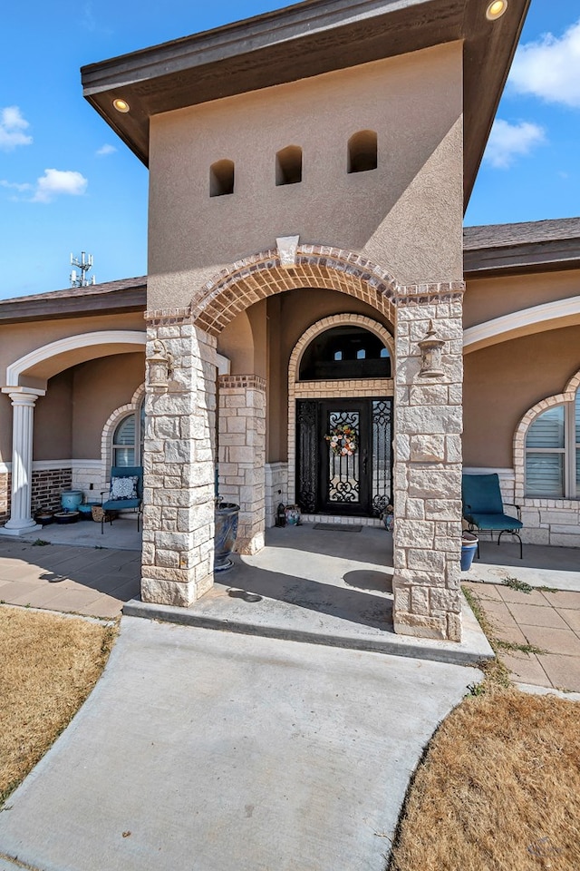 view of exterior entry with stone siding and stucco siding