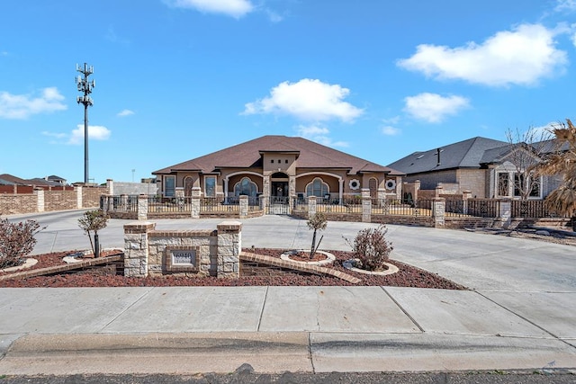 view of front of home with a fenced front yard and curved driveway