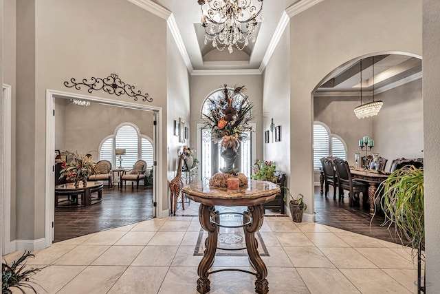 foyer entrance featuring tile patterned floors, a notable chandelier, arched walkways, and crown molding