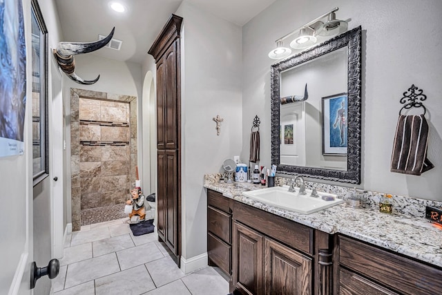 bathroom featuring vanity, baseboards, visible vents, a tile shower, and tile patterned floors