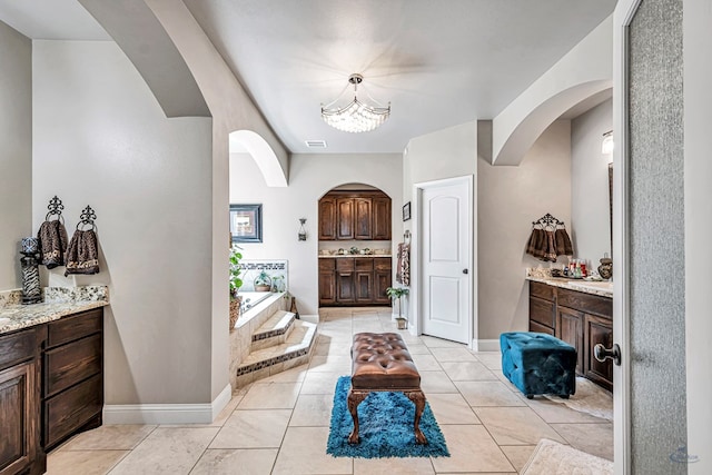 full bath with baseboards, visible vents, two vanities, a garden tub, and a chandelier