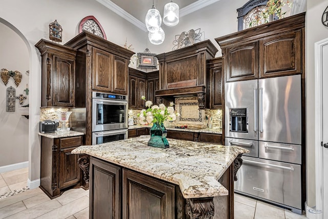 kitchen with arched walkways, dark brown cabinetry, appliances with stainless steel finishes, and crown molding