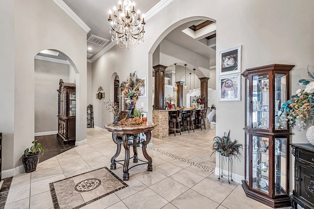 tiled foyer entrance with visible vents, arched walkways, crown molding, baseboards, and a towering ceiling